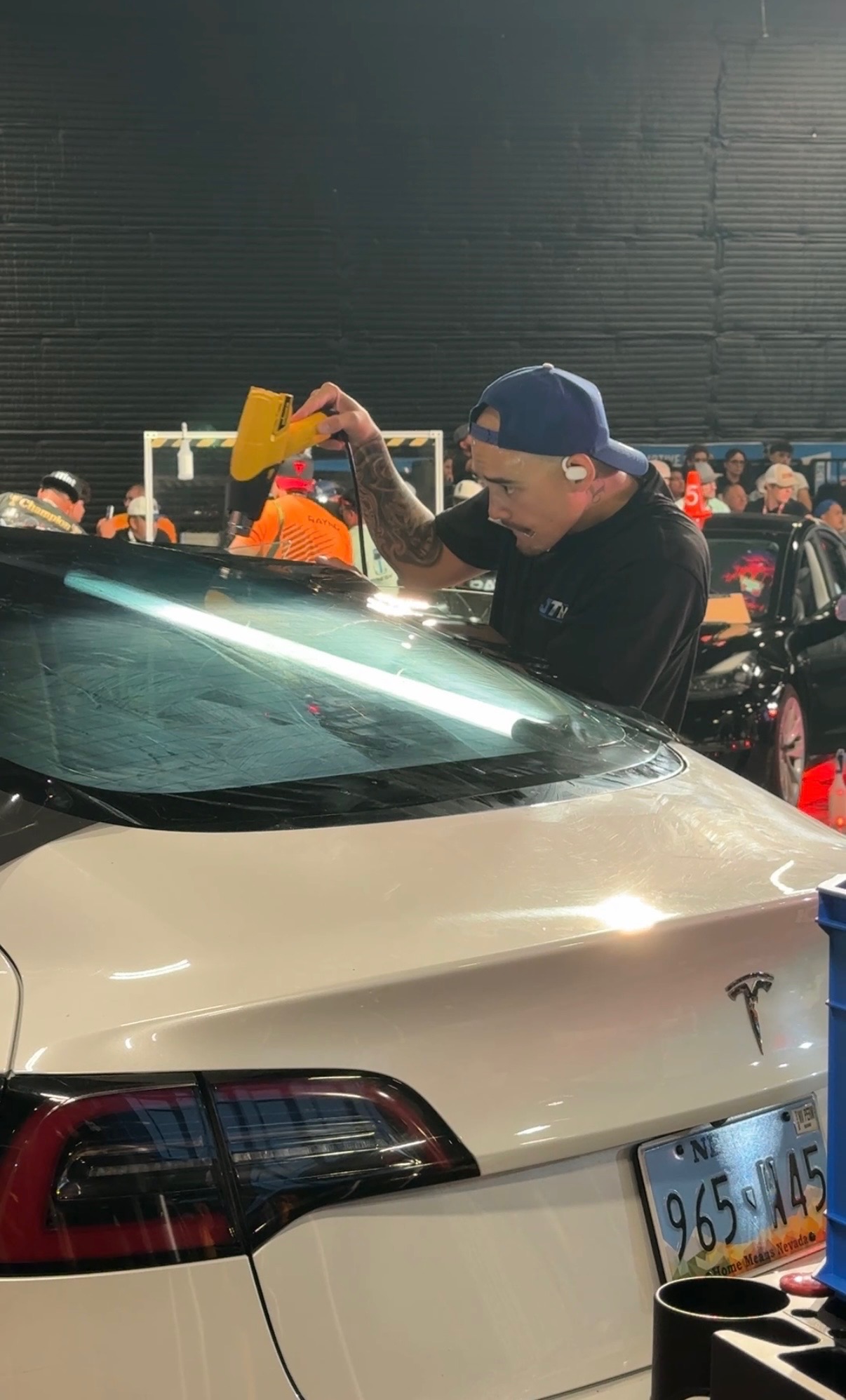 Award-winning ceramic tint install by JTINT owner — heat shrinking film on a Tesla rear windshield at the tint championship