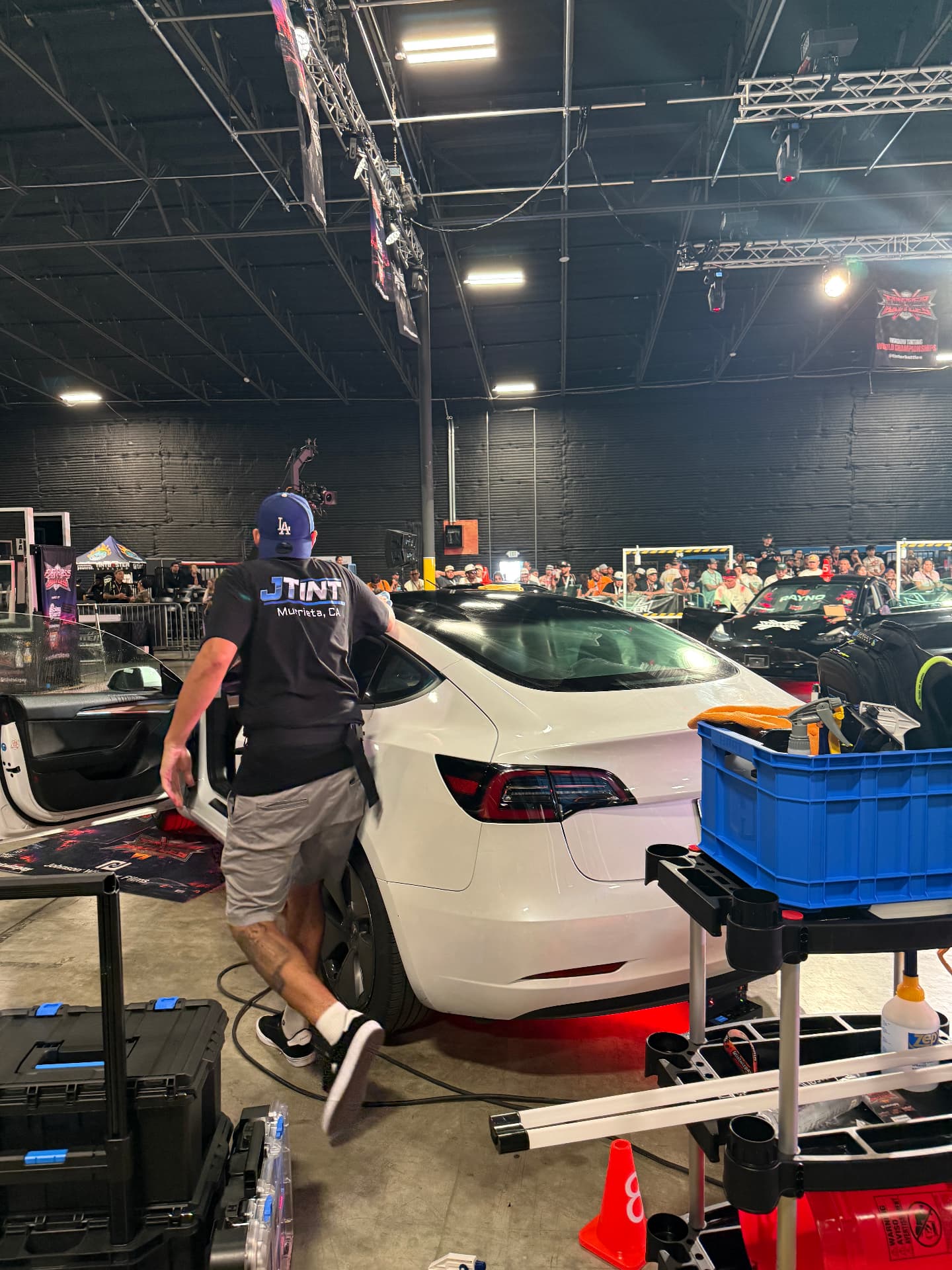JTINT owner JT tinting a white Tesla Model 3 on the competition floor at the window tinting World Championships